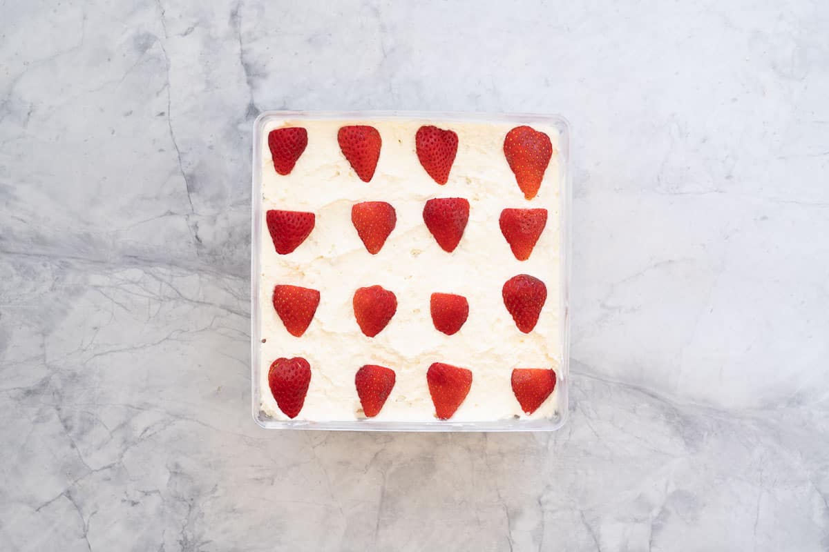 The top layer of cream of an ice box cake, decorated with sliced strawberries.