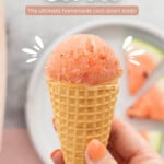 A waffle cone topped with pink sorbet being held up to the camera with text overlay for Pinterest.