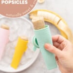 A banana popsicle in a aqua blue silicone squeeze tube being held above a plate of ice and more popsicles with text overlay for pinterest.