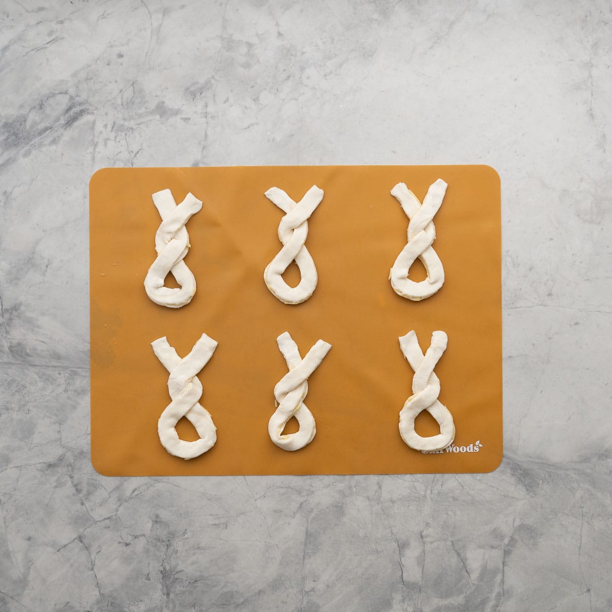 Puff pastry bunny twists on a silicone baking mat ready to go into the oven 