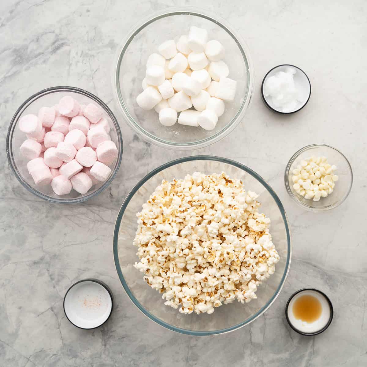 The ingredients to make popcorn balls laid out on a bench top in mismatched bowls. 