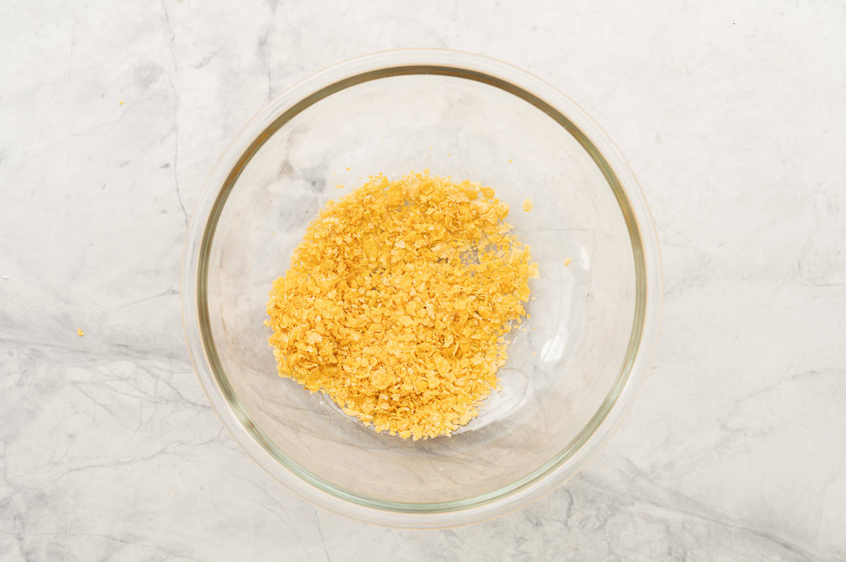 Crushed cornflakes in a large glass mixing bowl. 