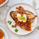 Baked beans on toast topped with a hard boiled eggs and sprigs of parsley.