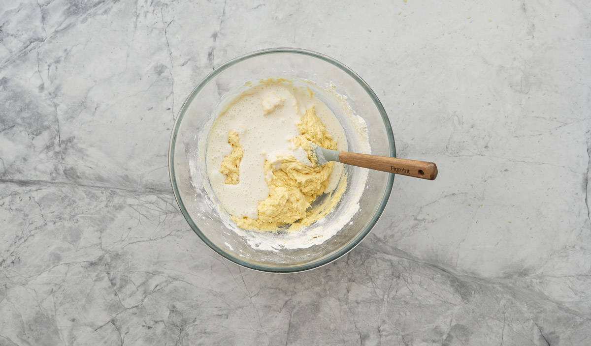 Flour and milk mixtures added to the creamed sugar, butter and eggs in a bowl on the bench 