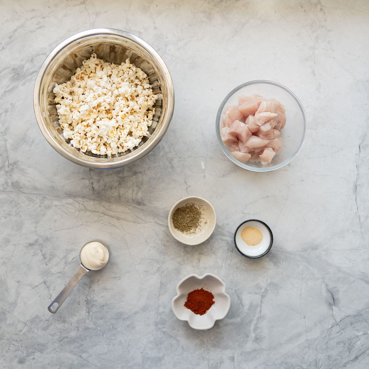 The ingredients to make popcorn chicken laid out on a bench top. 