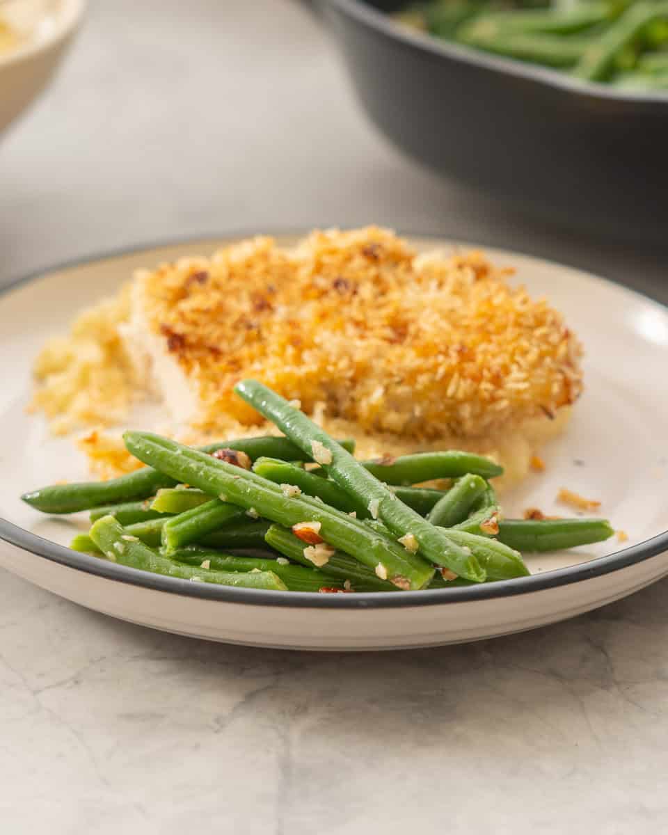 A dinner plate with garlic green beans and crumbed chicken. 