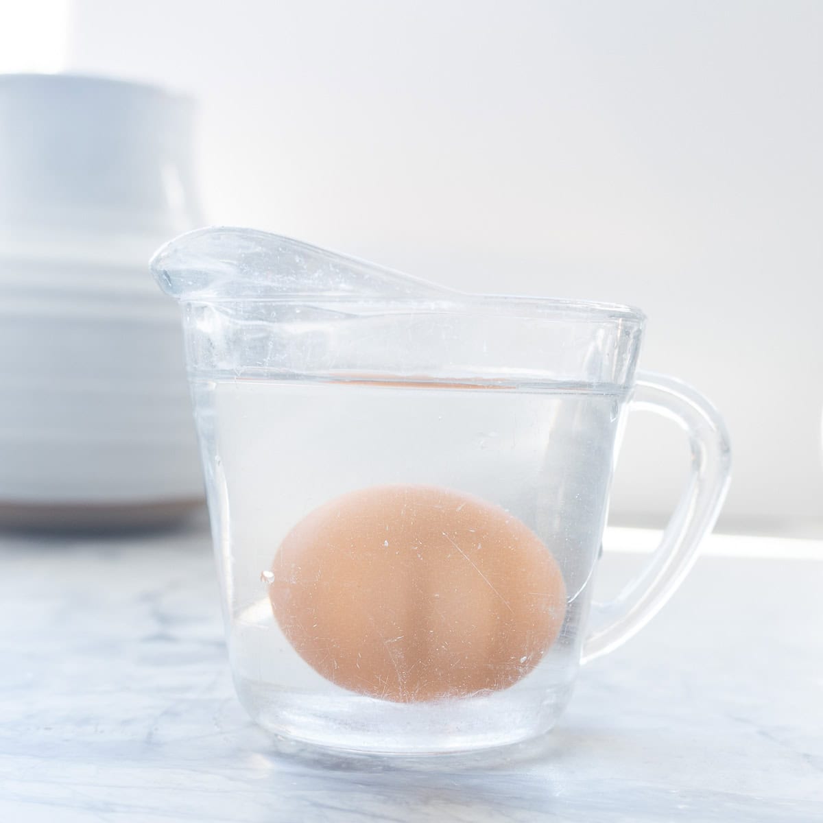 An egg in a microwave proof cup filled with water.