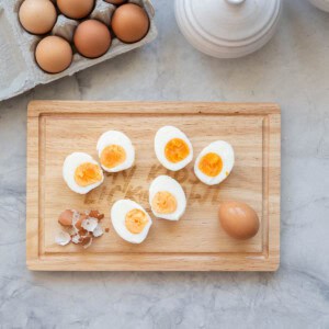 5 halves of hard boiled eggs on a wooden chopping board.