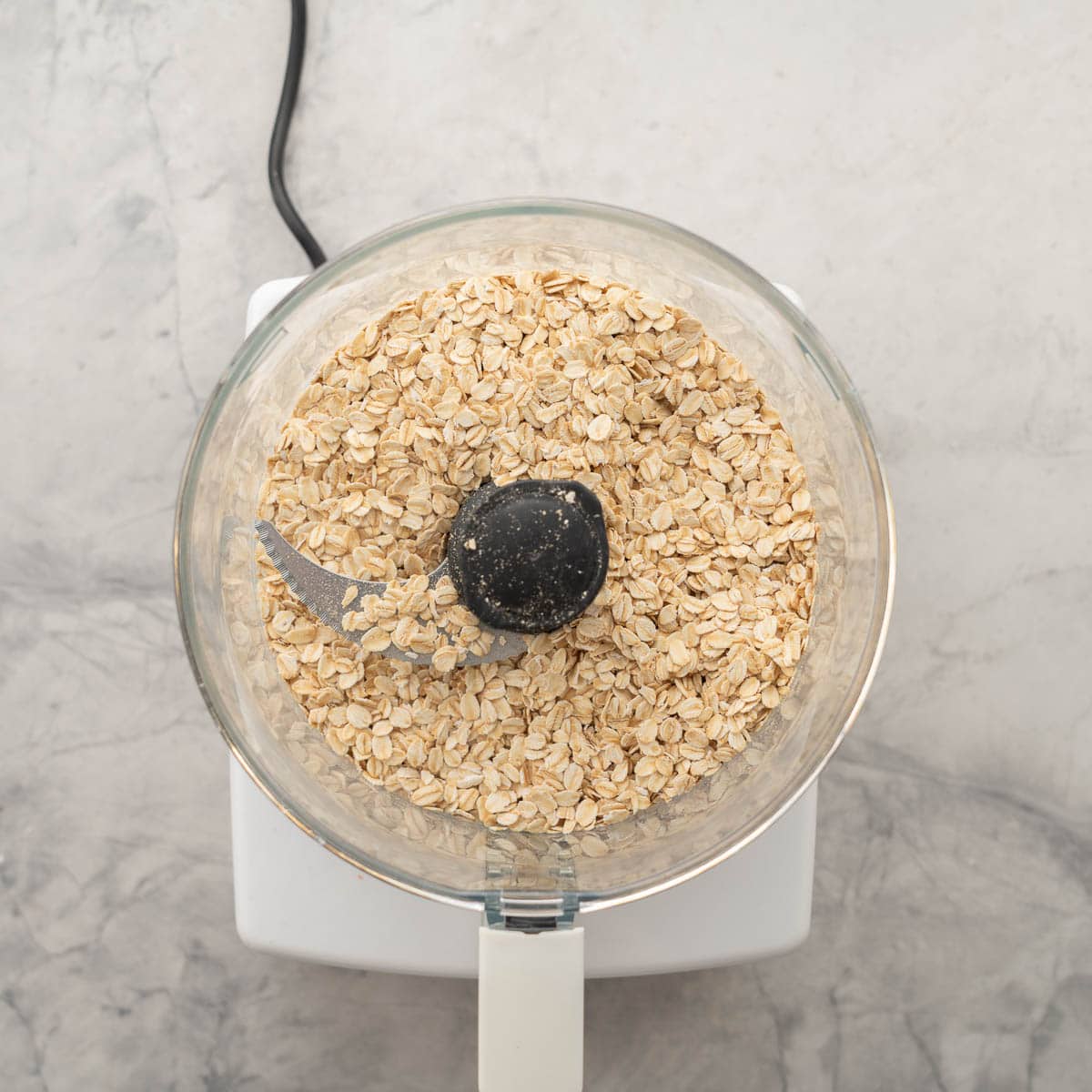 A food processor full of oats resting on the bench 