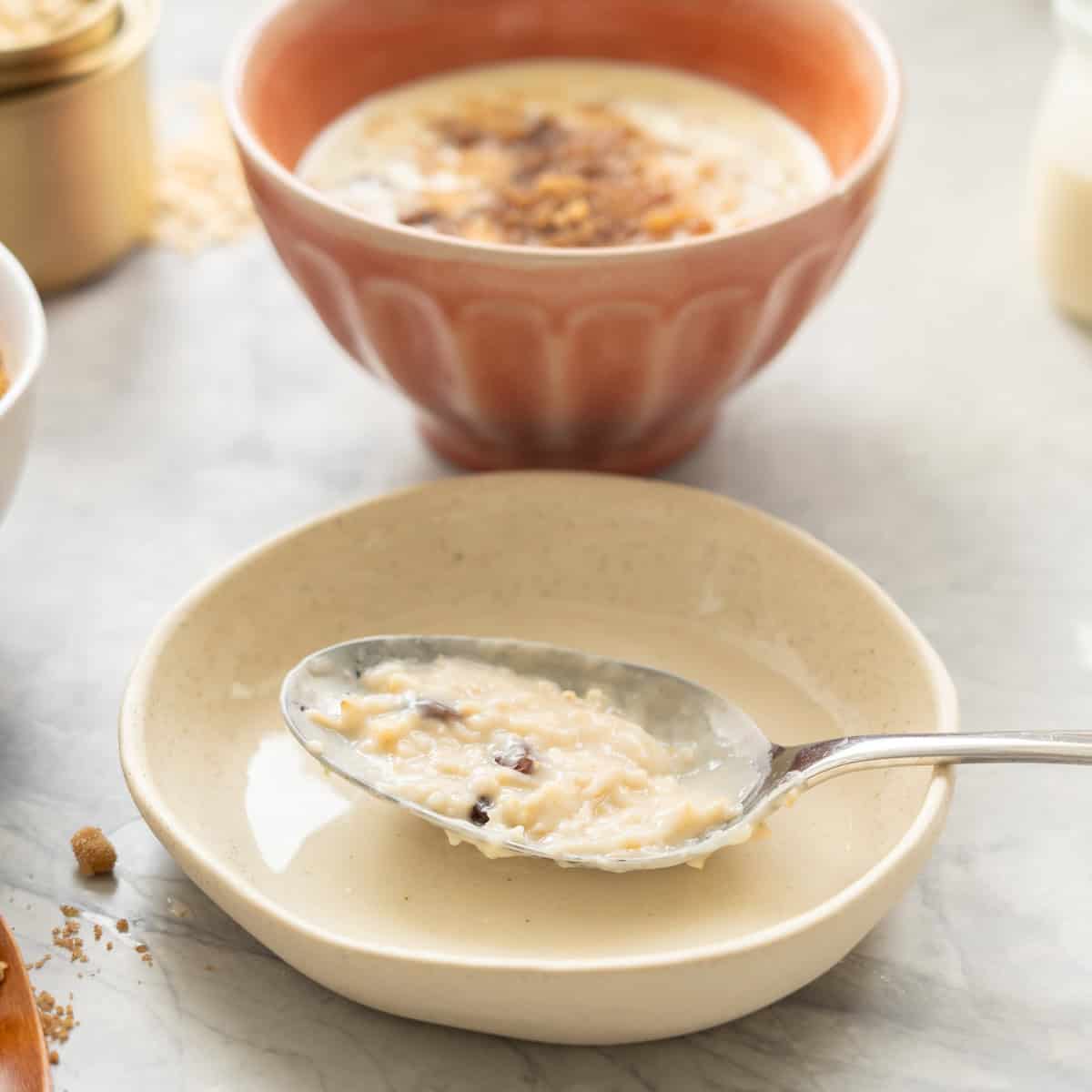 A serving spoon coated in porridge resting on a side plate showing the creamy sauce created when the starches release from oat meal. 