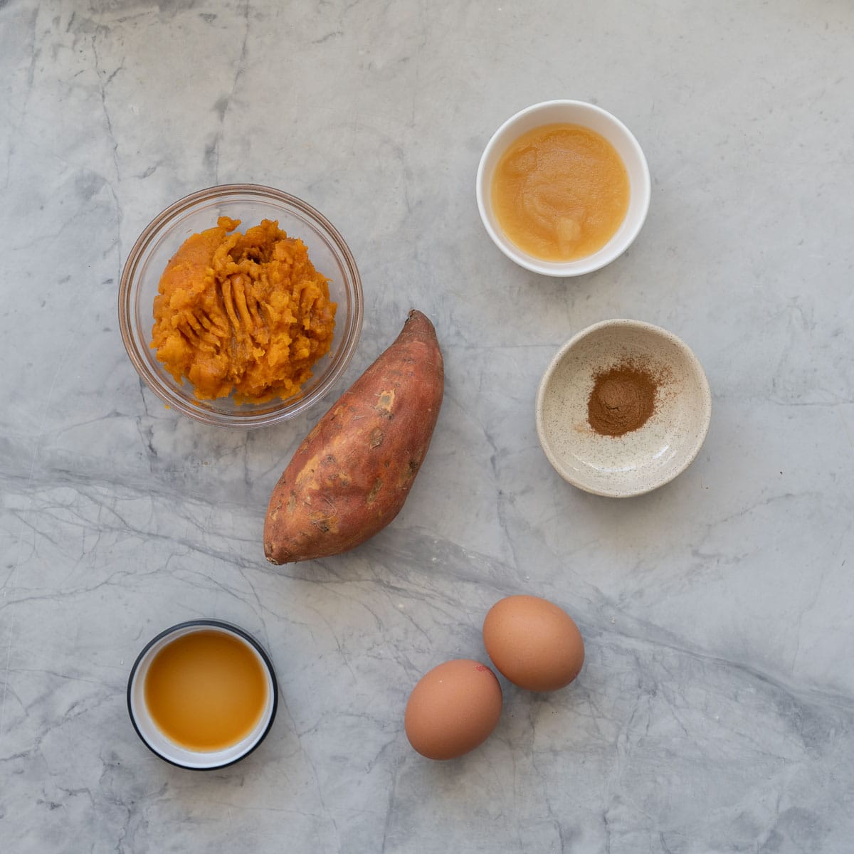 The ingredients to make sweet potato pancakes measured and laid out on a marble bench top.