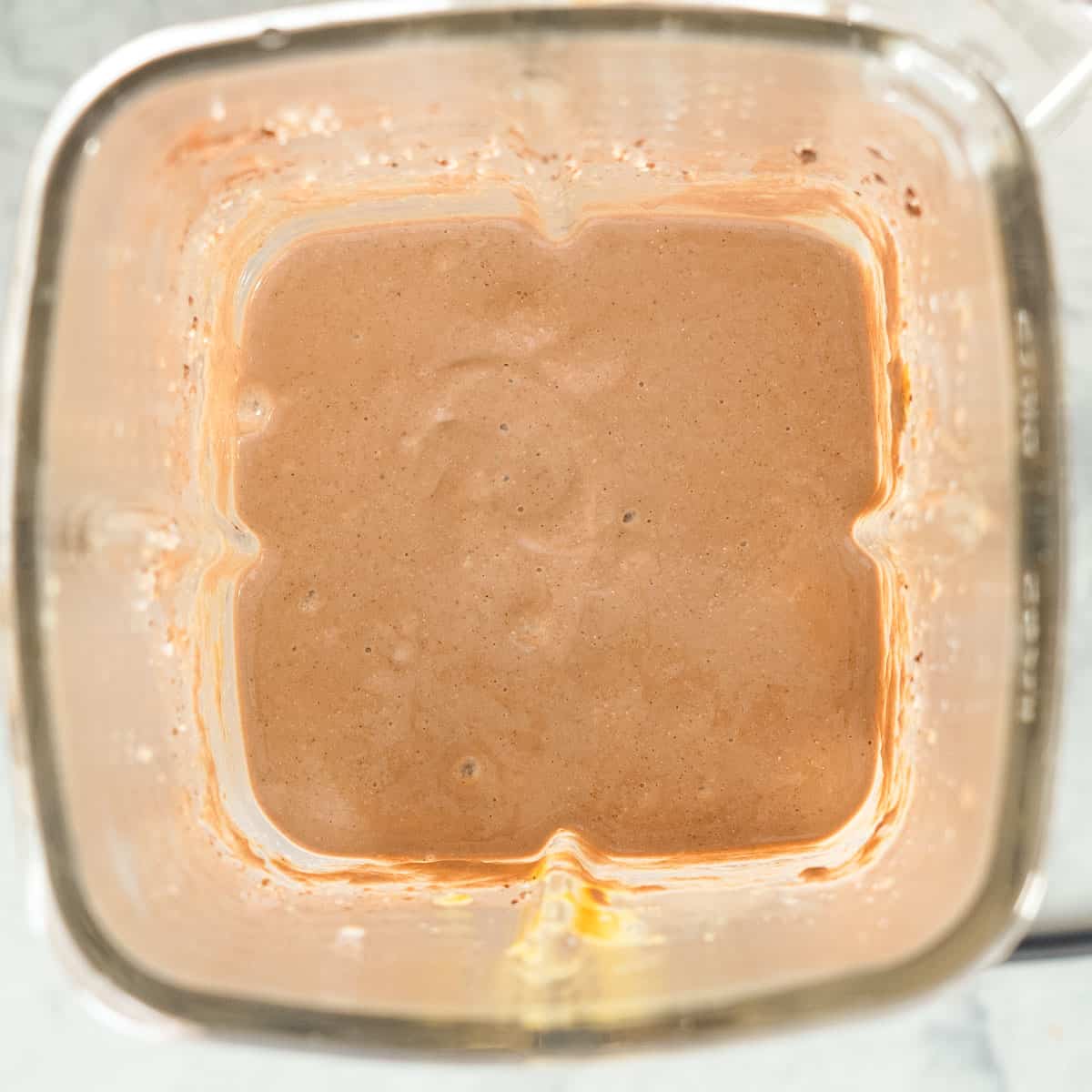 Looking down into a blender jug of smooth thick chocolate smoothie.
