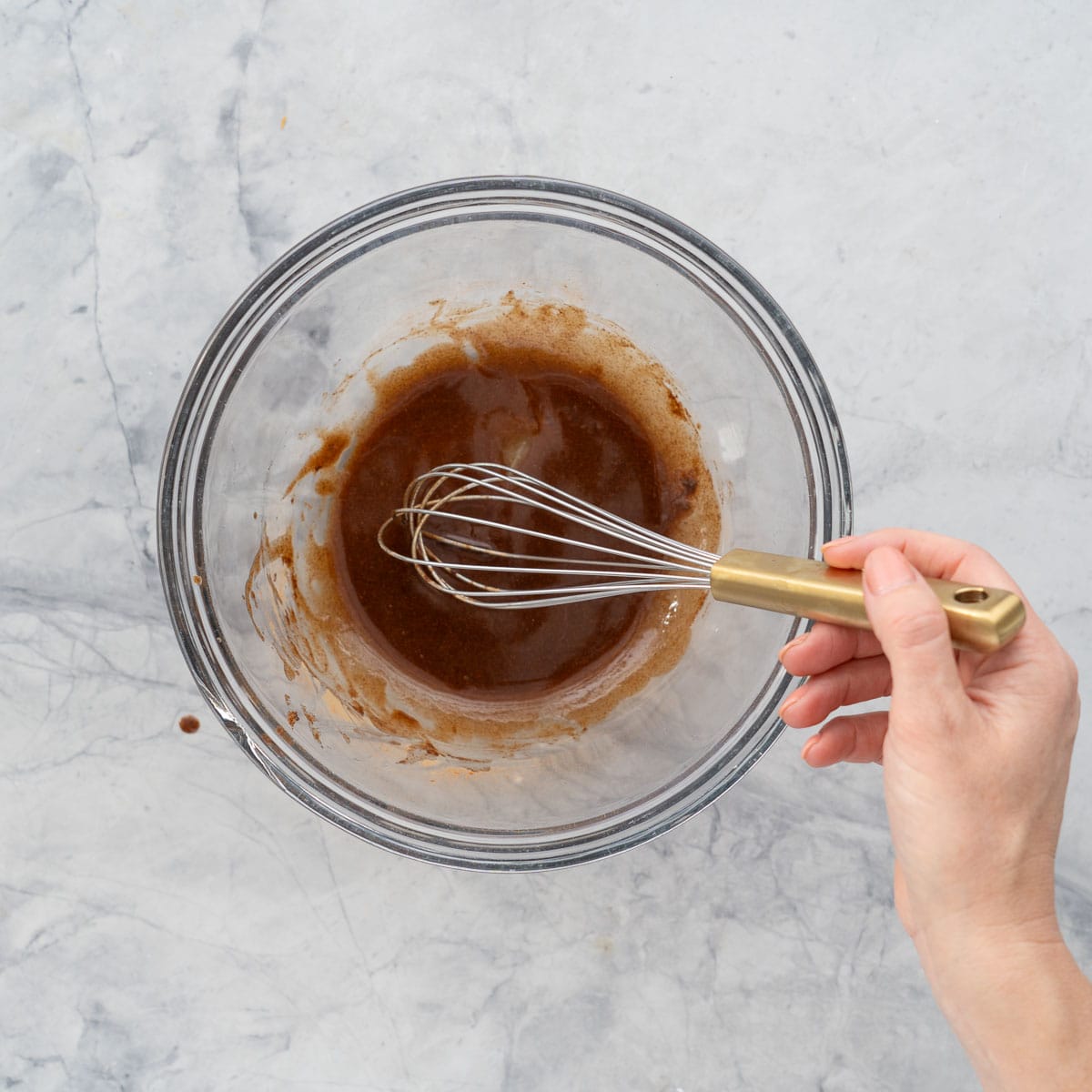 A mixing bowl with a cinnamon and butter mixture being combined with a whisk. 