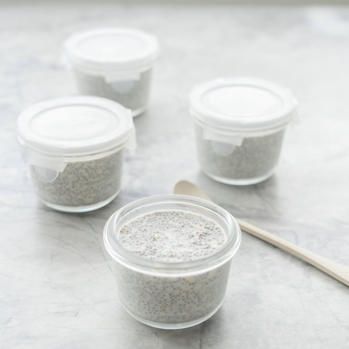Four small glass containers filled with chia seed pudding.
