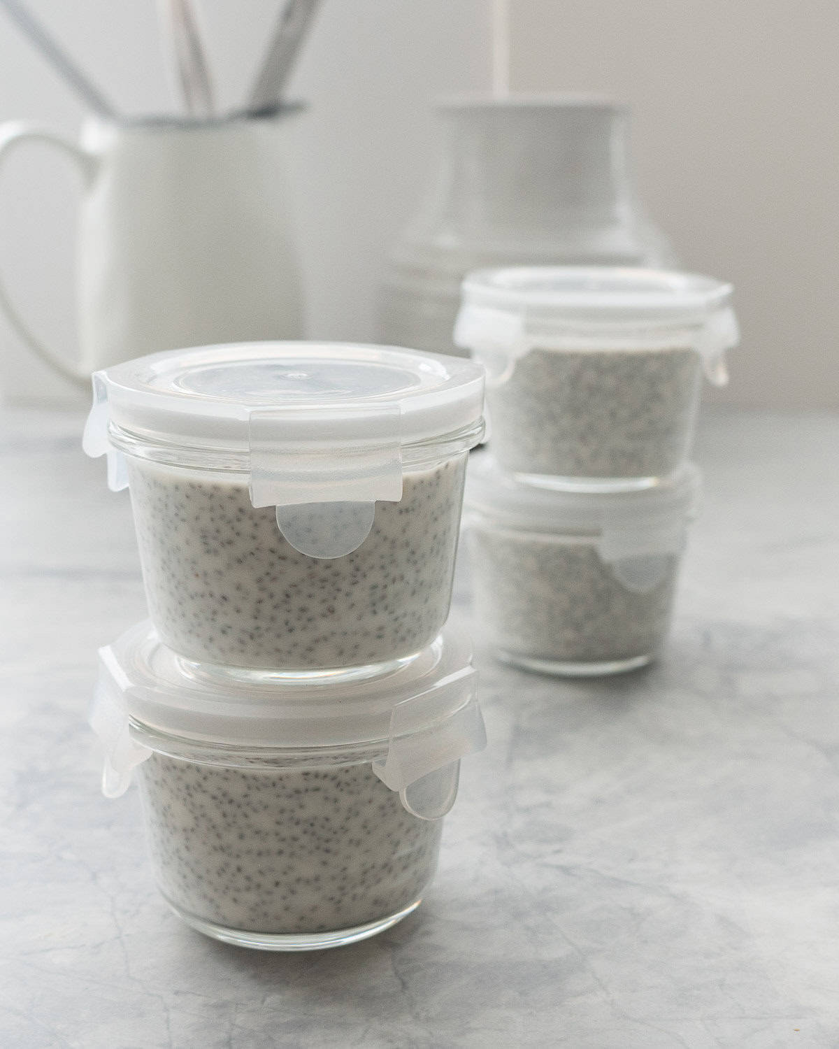 2 stacks of 2 containers filled with coconut chia pudding with lids on.