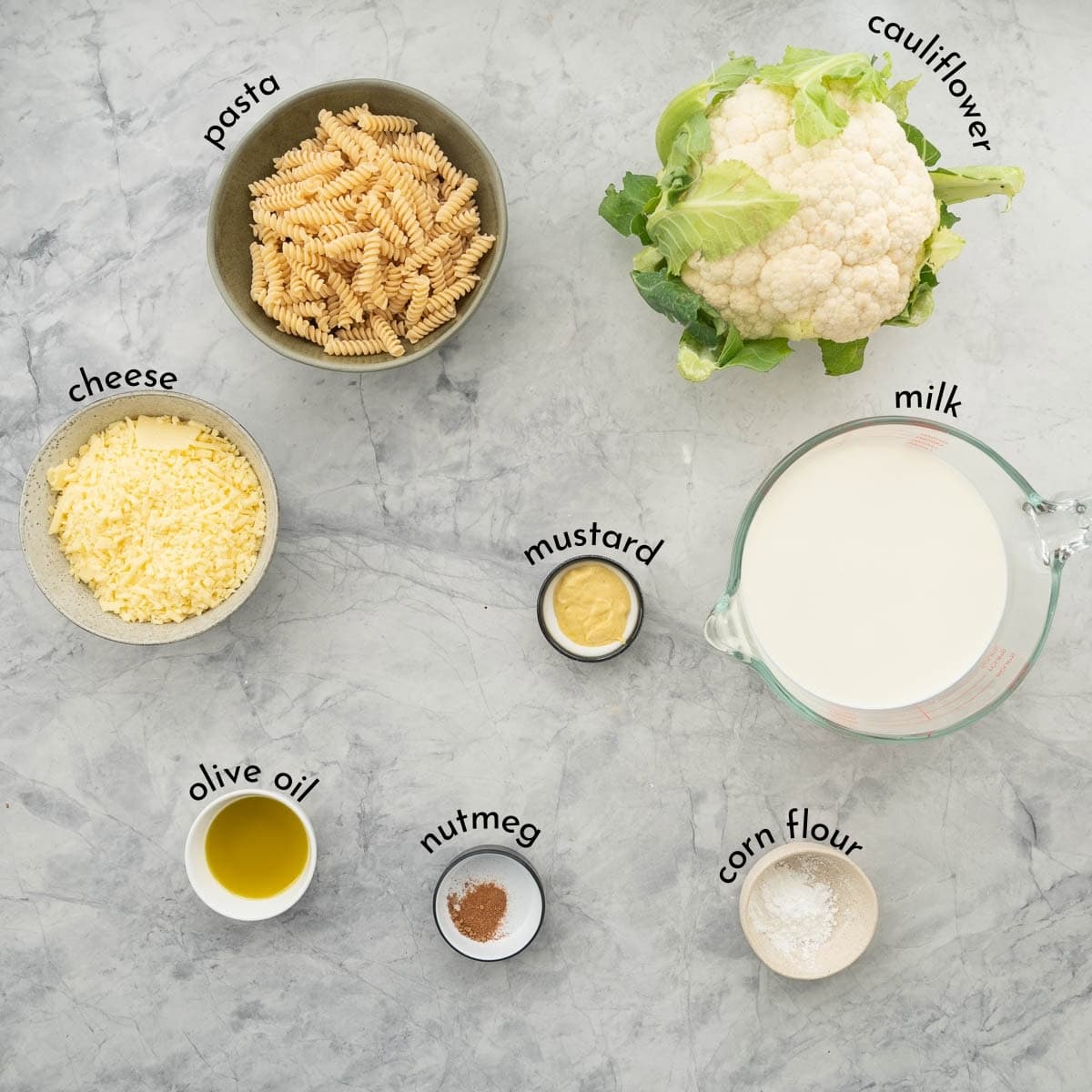 Ingredients for Cauliflower pasta bake measured and laid out on bench top with text overlay labels.