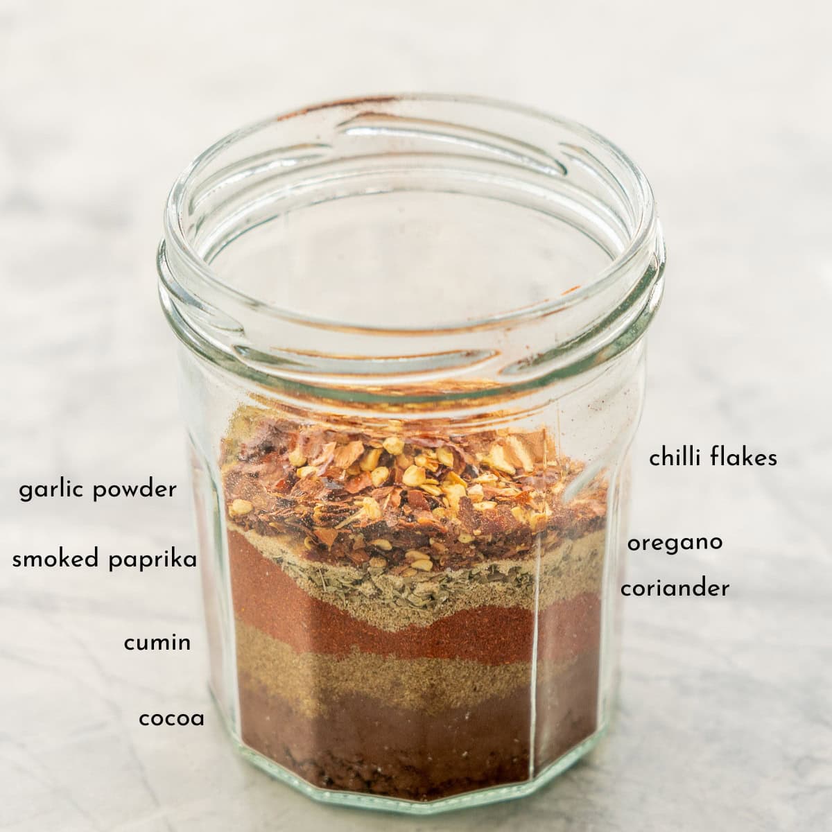 Mexican seasoning ingredients layered in a jar with txt overlay.