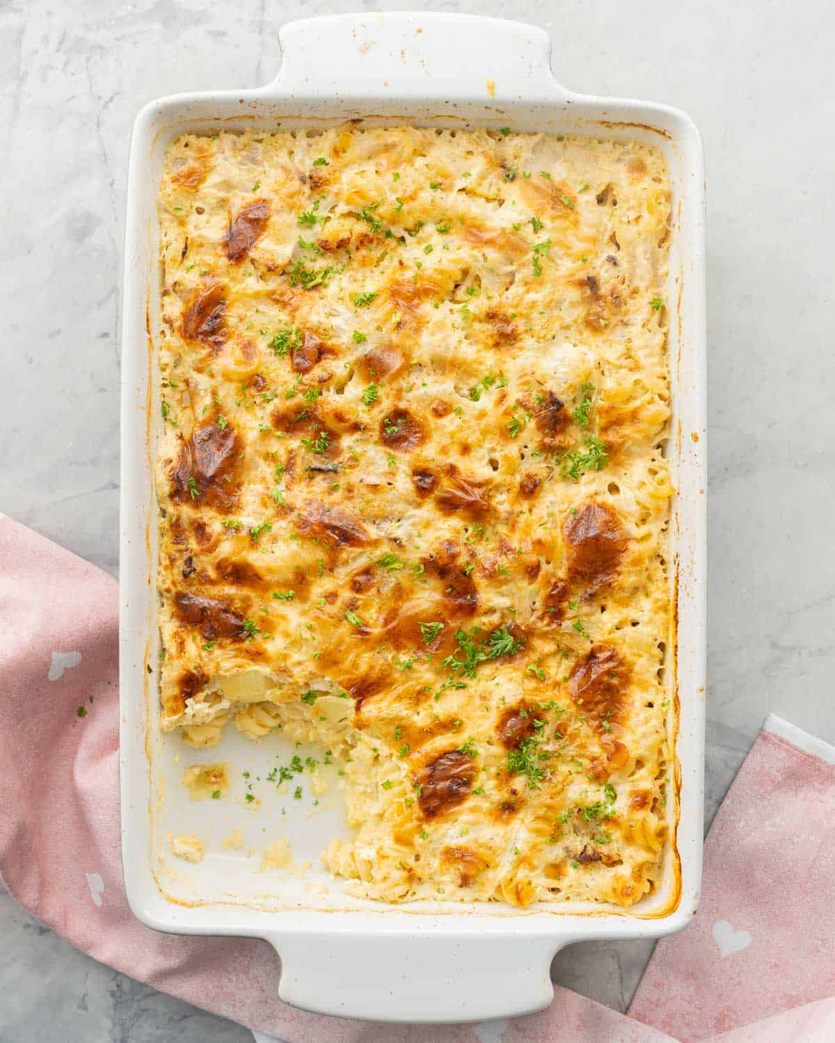 Cauliflower bake in baking dish with a serving scooped from the corner.