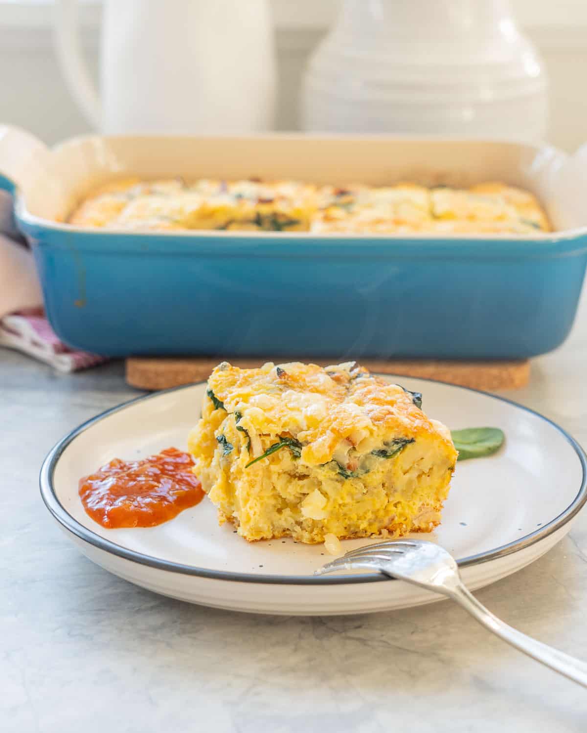 A piece of egg hash brown bake served on a plate with fork