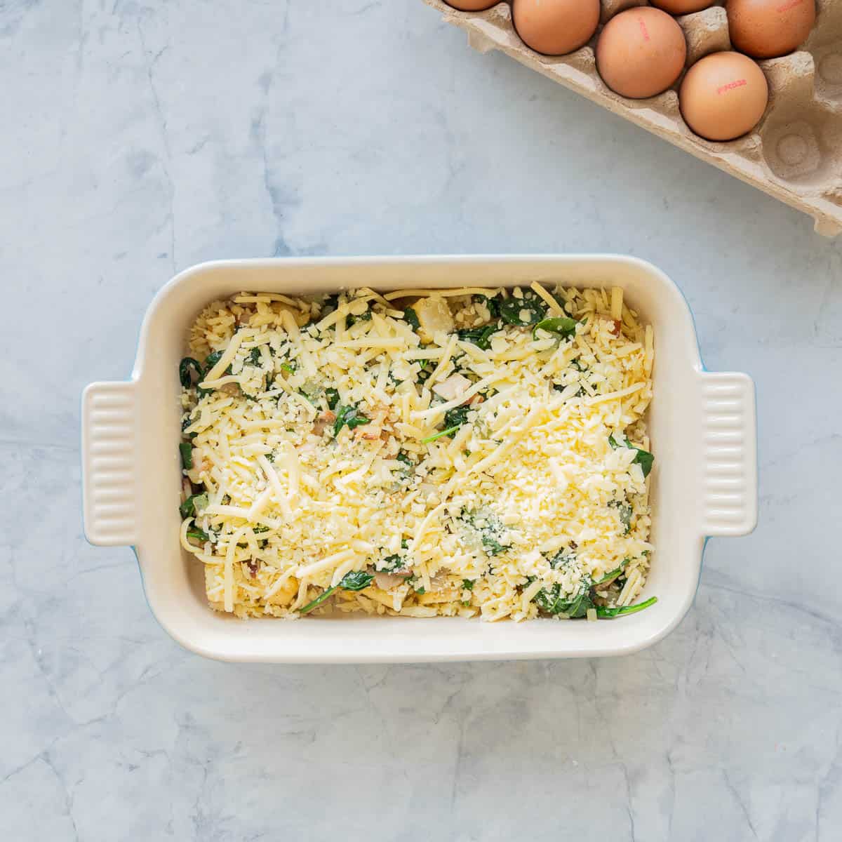 Grated cheese layered on top of the all the other ingredients in baking dish.