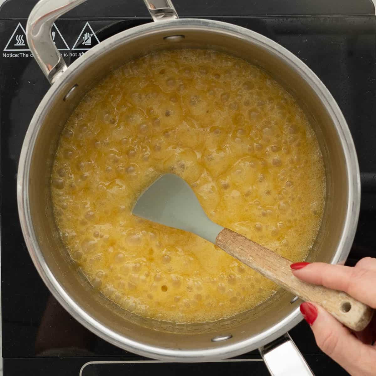 Ingredients being stirred while boiling in a pot on the stove.