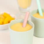 Close up of the top of a green toddler cup filled with peach coloured smoothie.