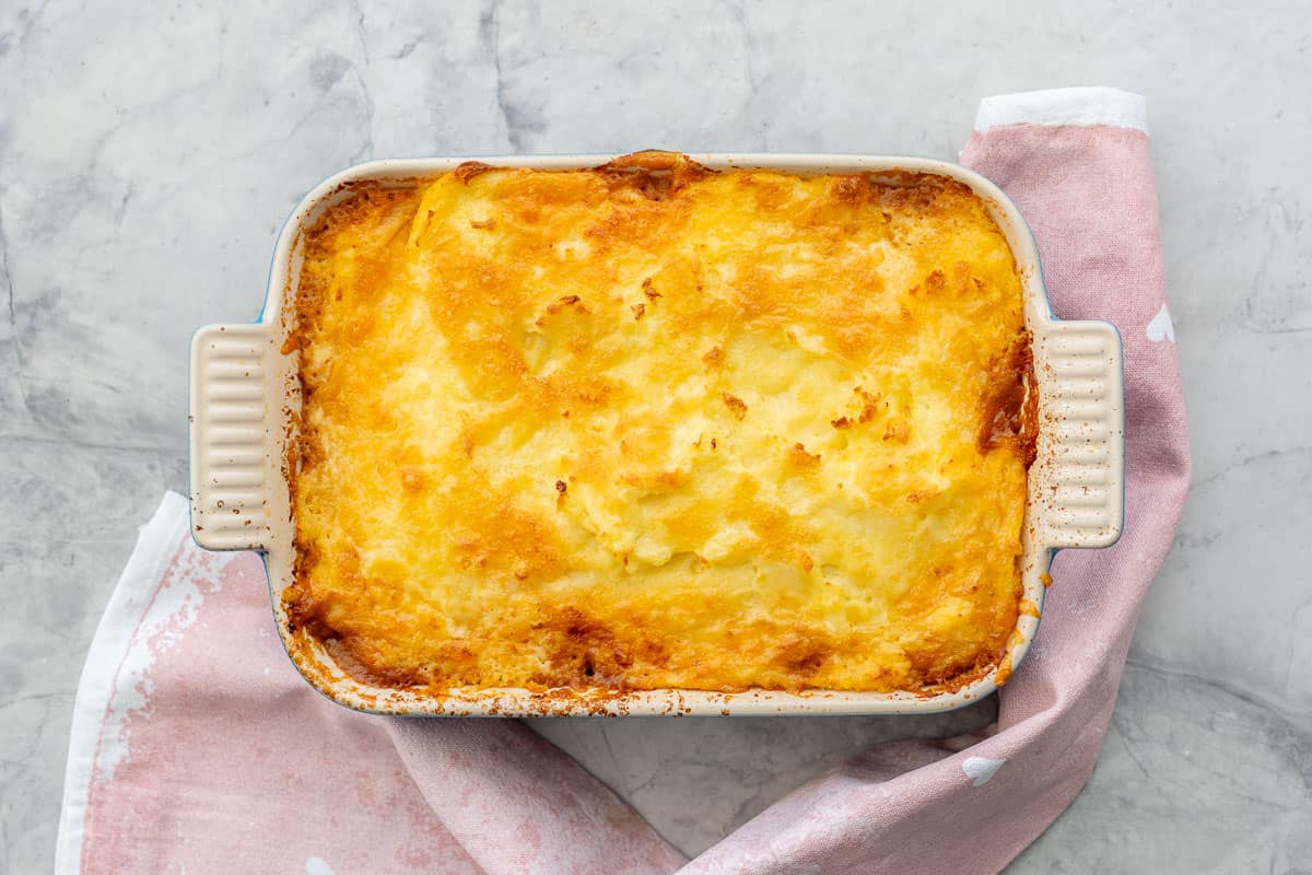 Baking dish of shepherds pie hot out of oven with crispy melted cheese on top.