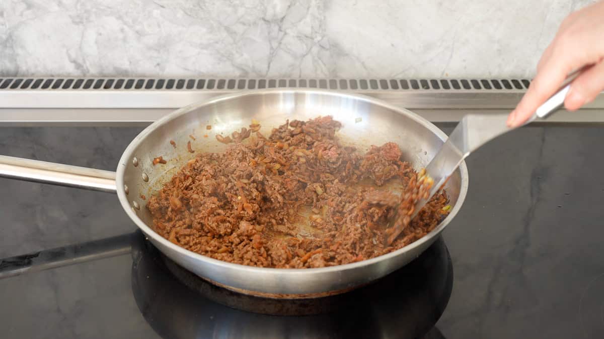 Minced beef browning in a stainless steel fry pan.