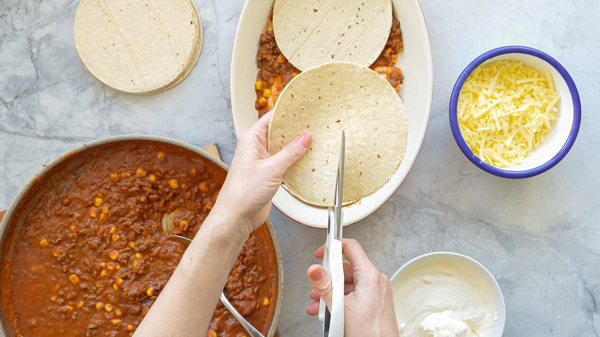 Tortilla being cut in half with a pair of scissors.