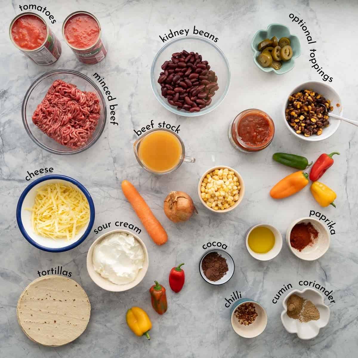 The ingredients to make tortilla casserole laid out on a bench top with text overlay labels.