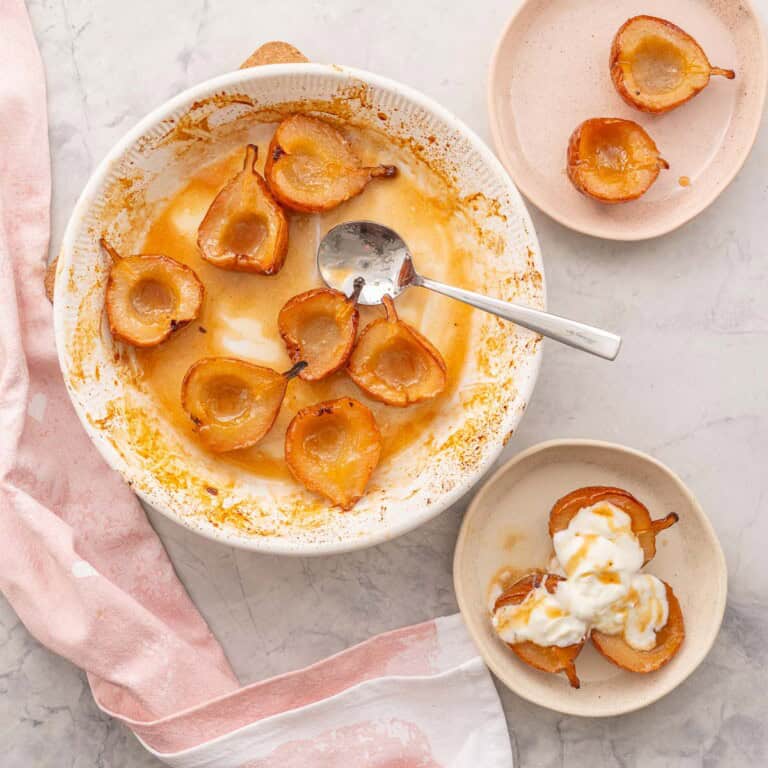 Baked pears caramelised in baking dish with serving spoon, Three caramelised baked pears served on a plate with greek yogurt and a drizzle of maple syrup on top.