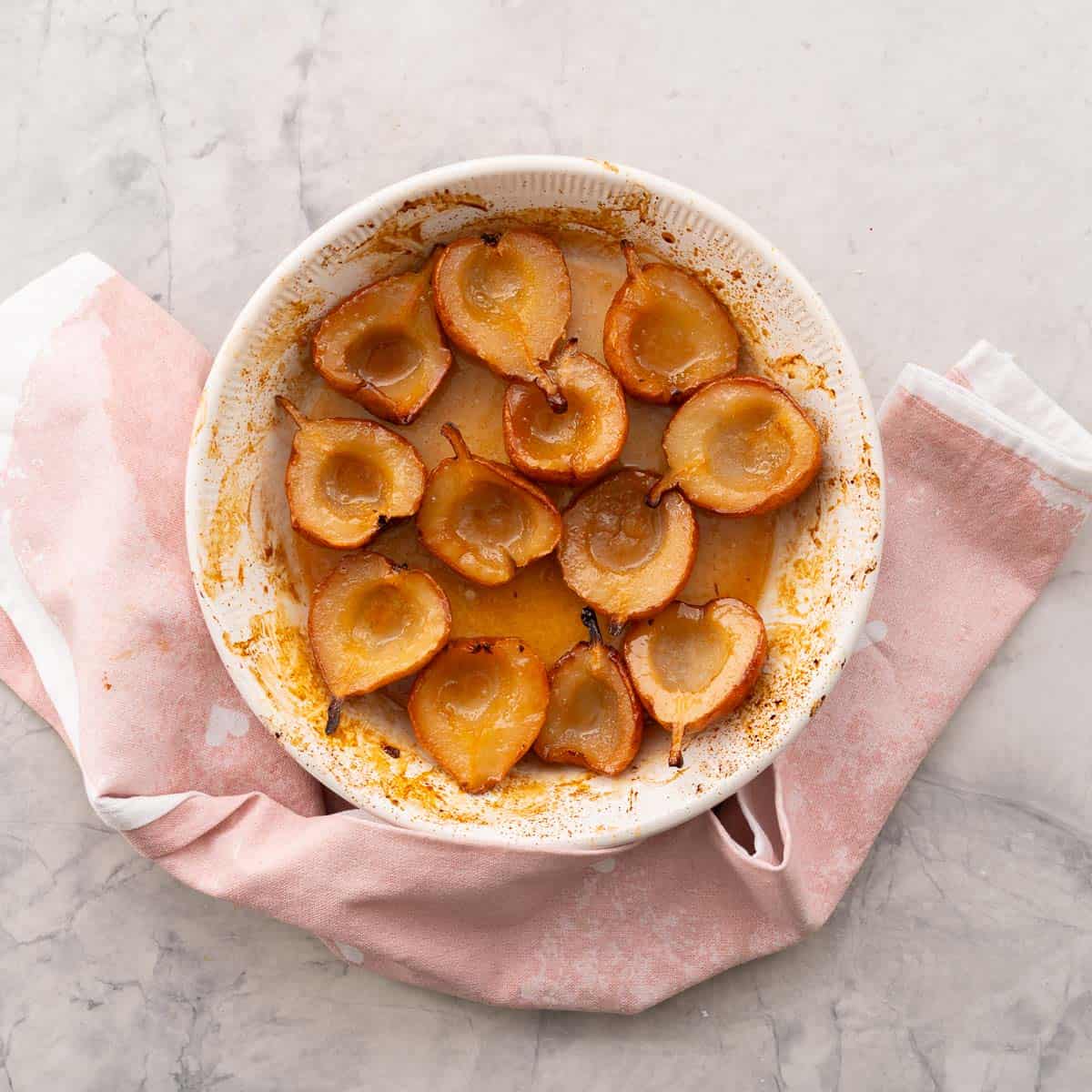 Cooked baked pears caramelised in baking dish.