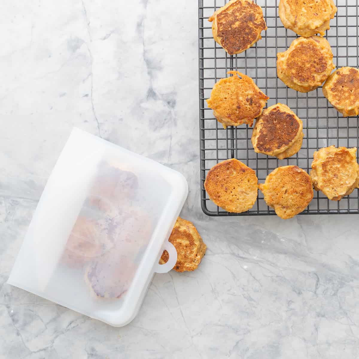 Carrot cake pancakes on baking cooling rack, some in a reusable airtight storage bag on benchtop.