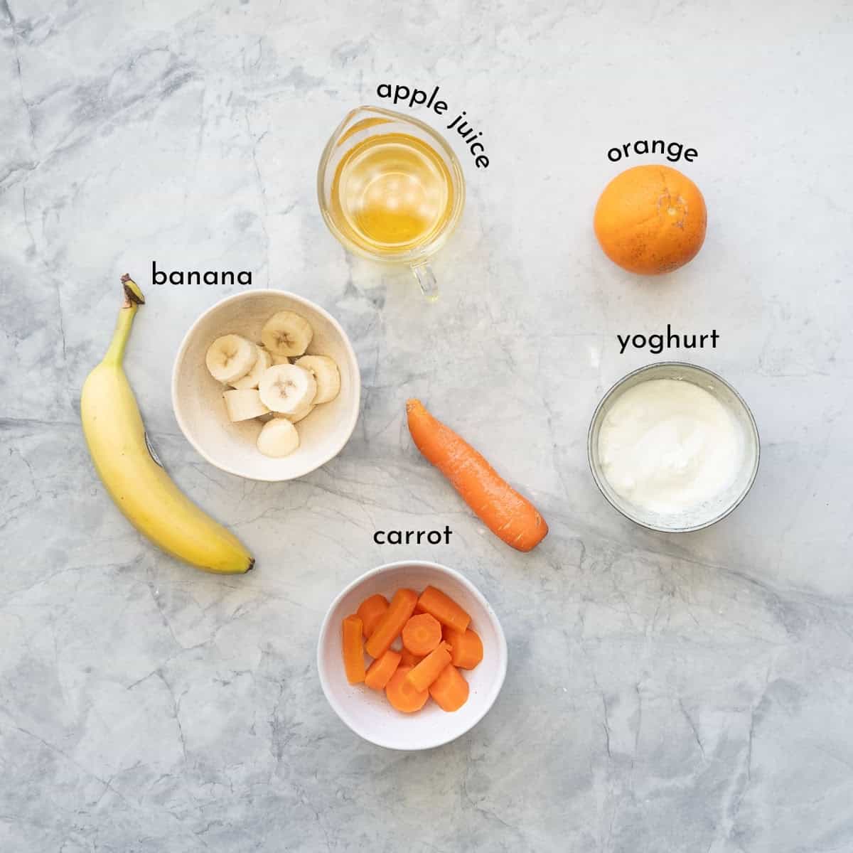 Carrot smoothie ingredients portioned and laid out on bench top with text overlay.