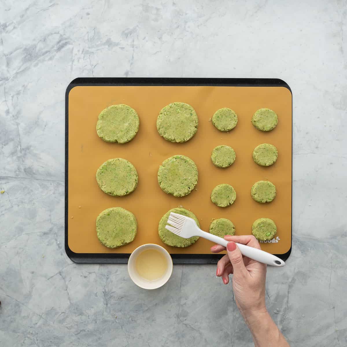 Oil being brushed onto chickpea patties.