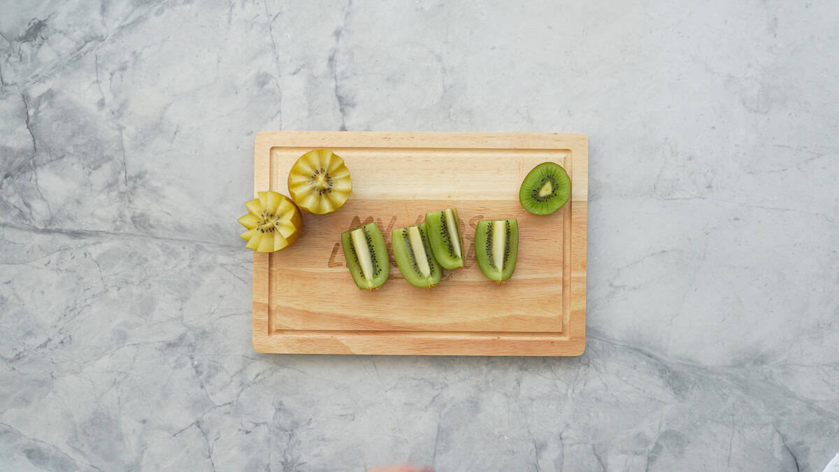 A green kiwi with one end removed cut lengthways into quarters. 