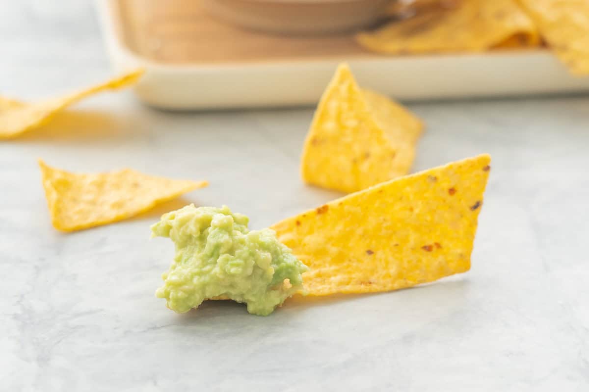 Nacho chip laid on bench top dipped in Guacamole.