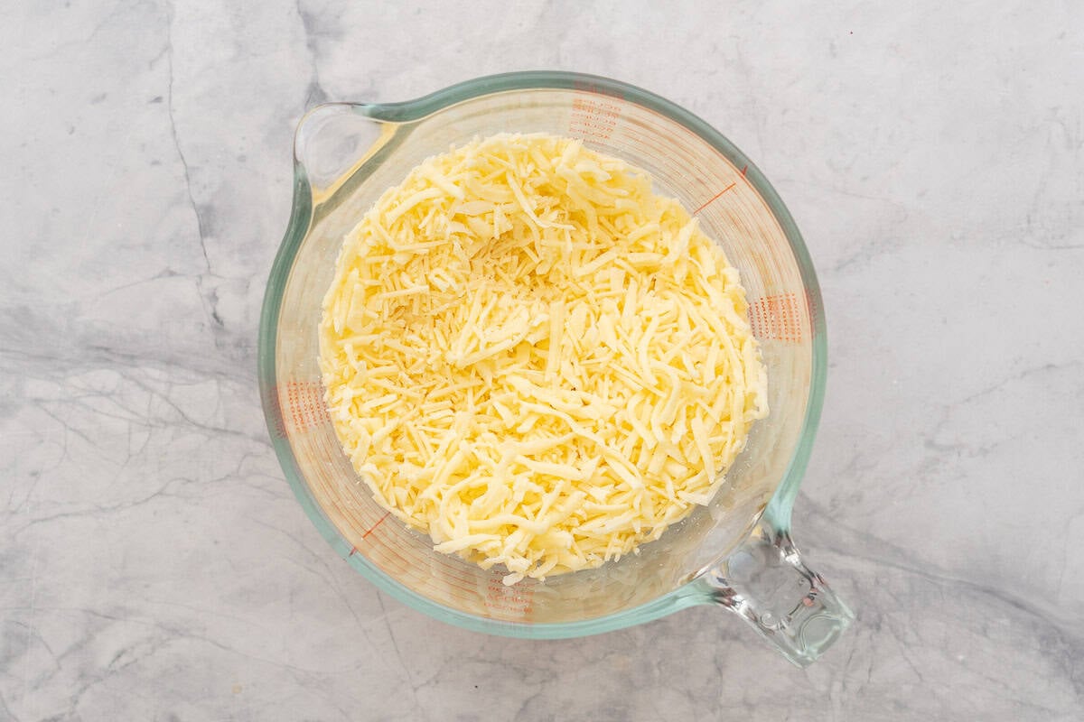 Grated Mozzarella and parmesan cheese in glass mixing bowl.