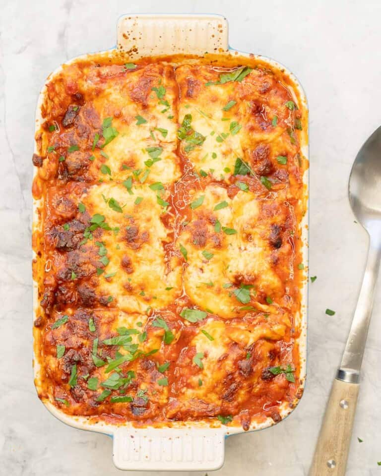 Lazy Lasagna in baking dish with serving spoon on bench top.