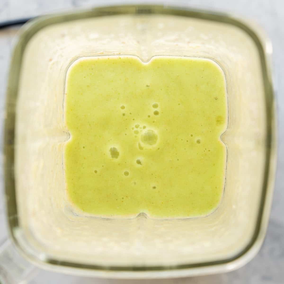 Looking down into smoothie maker with cucumber pineapple smoothie blended inside.