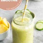 Green smoothie in a glass jar with yellow straw with text overlay: Pineapple cucumber smoothie, kid approved snack.