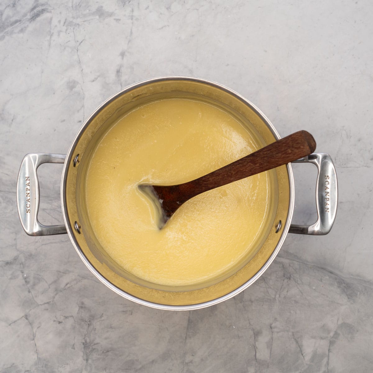 Potato soup in pot with wooden spoon.