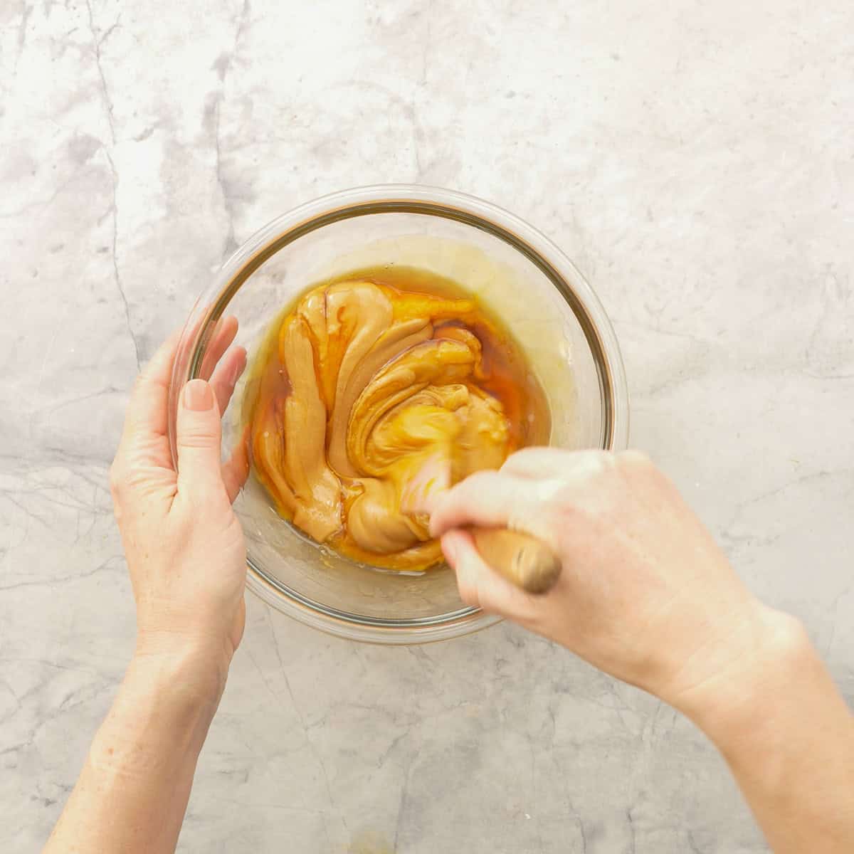 Wet ingredients for Pumpkin cookies being mixed together in bowl with wooden spoon.