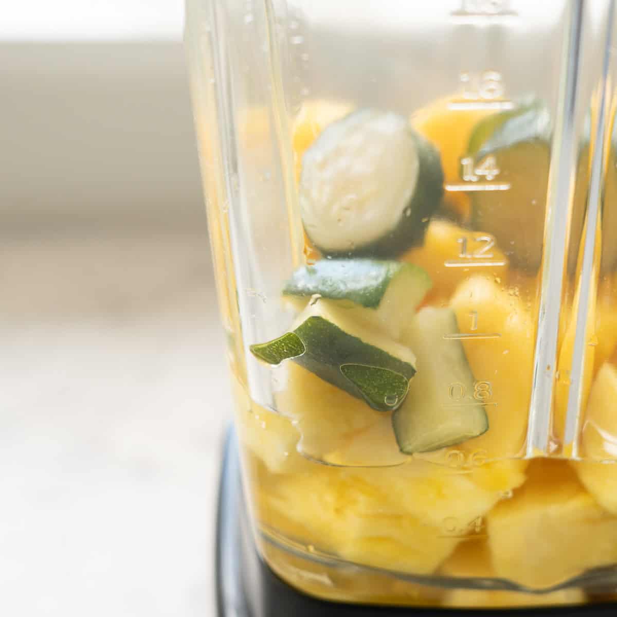 Close up of pineapple, zucchini and apple juice in blender.