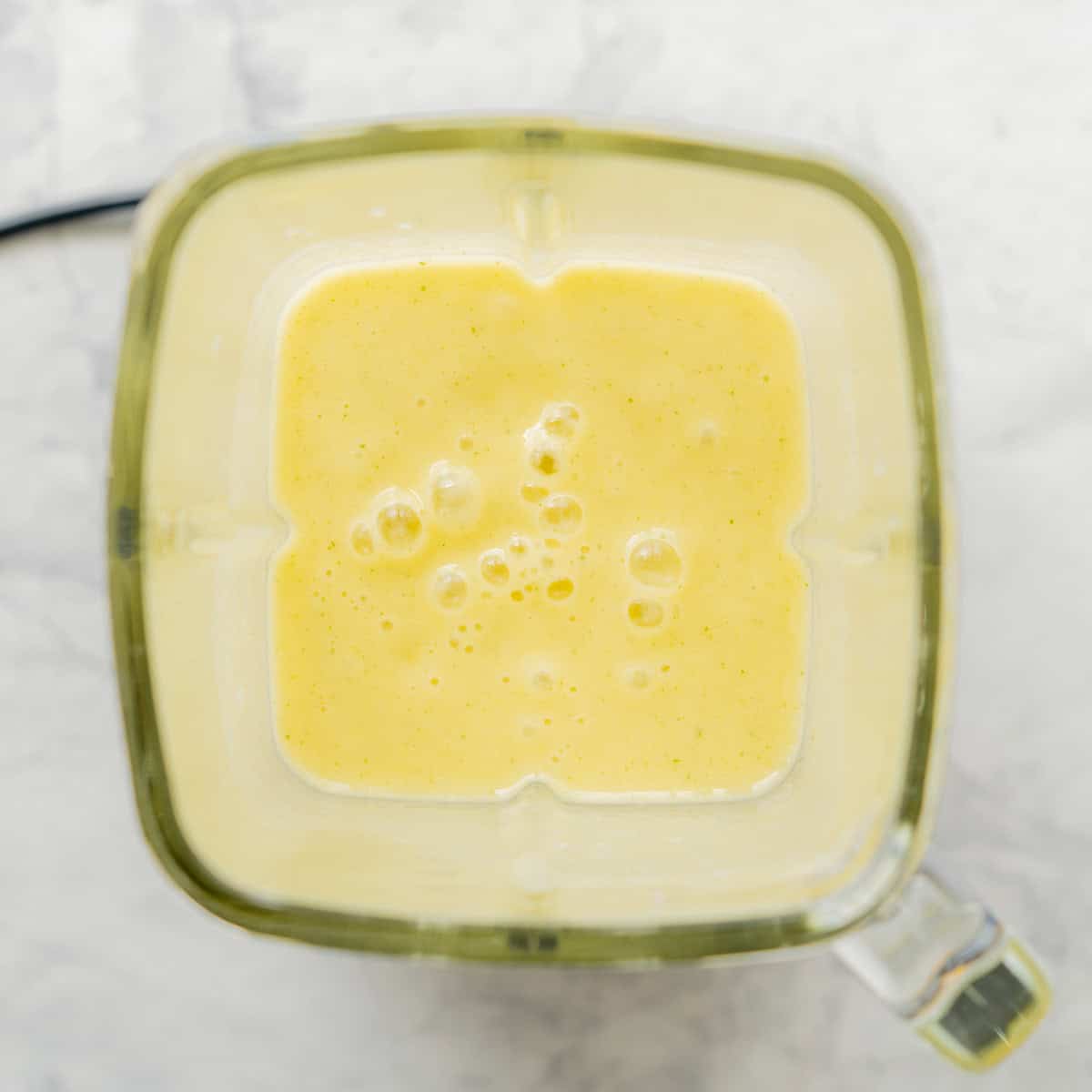 Looking down into blender with tropical smoothie blended inside.