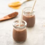 Chocolate peanut butter smoothie in small glass children's cups with paper straw.