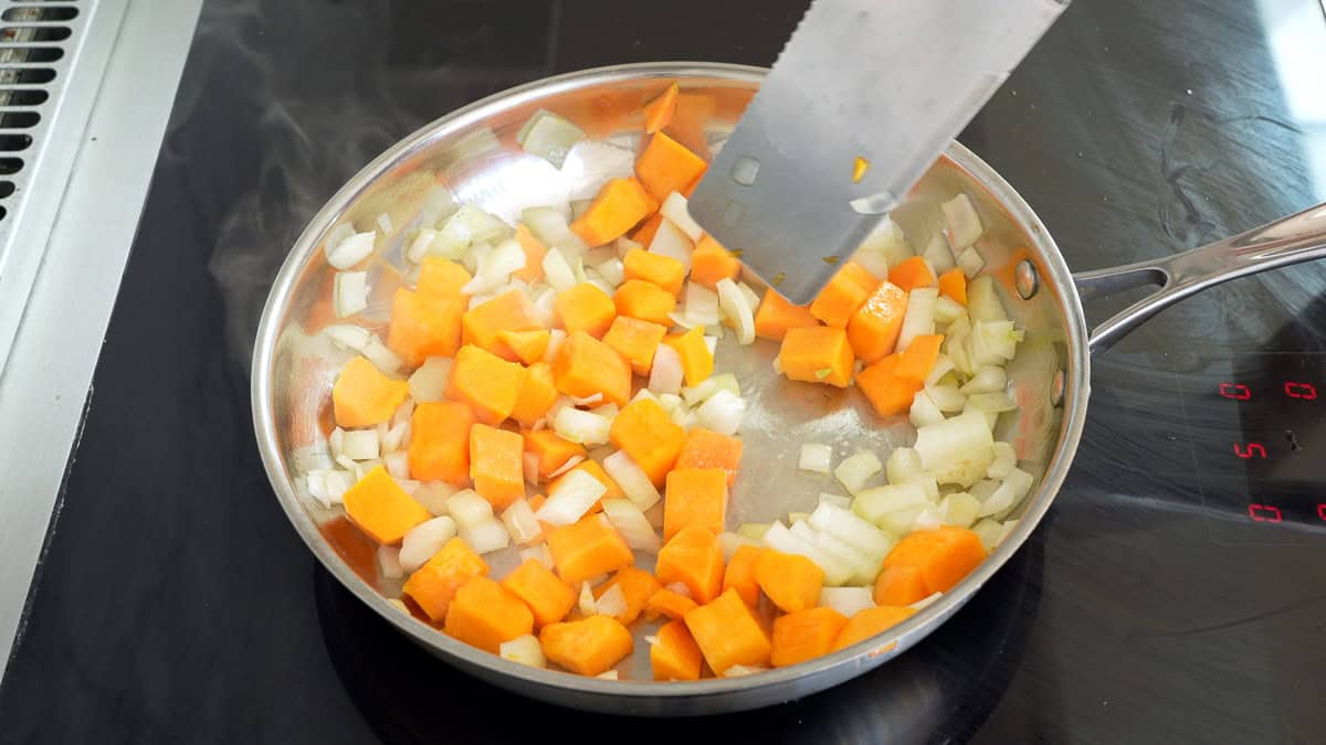 Onion and pumpkin sautéing in pan.