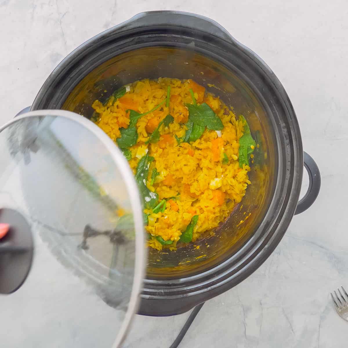 Risotto pumpkin in the crockpot with lid lifted off showing the liquid absorbed.