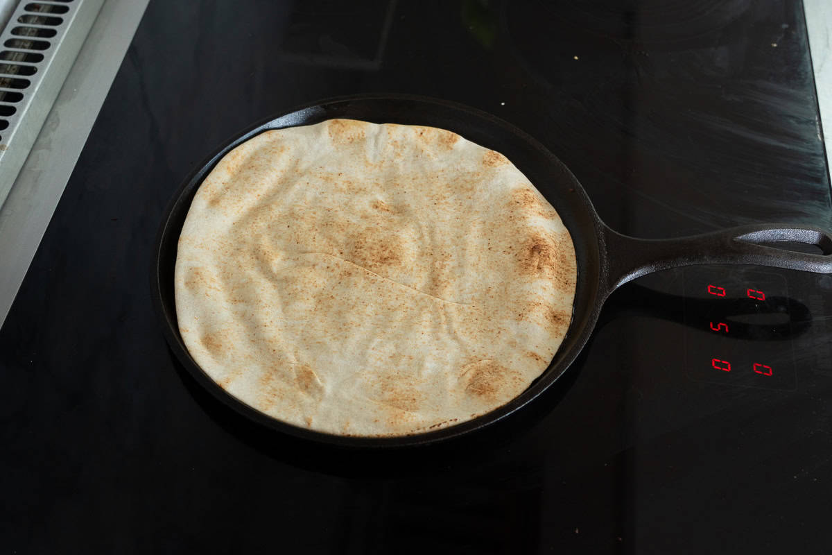 Pita bread in flat pan with falafel mix facedown into pan.