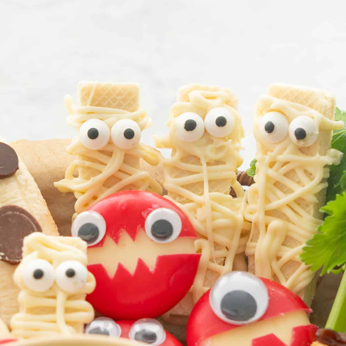 Three mummy wafer cookies and cheese monsters.